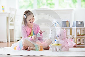 Little girl playing with doll house. Kid with toys