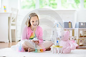 Little girl playing with doll house. Kid with toys