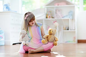 Little girl playing with doll house. Kid with toys