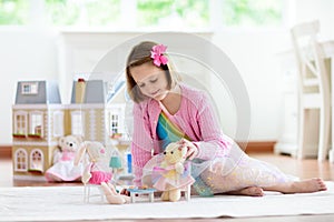 Little girl playing with doll house. Kid with toys