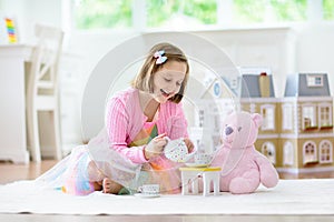 Little girl playing with doll house. Kid with toys