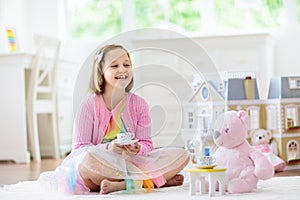 Little girl playing with doll house. Kid with toys