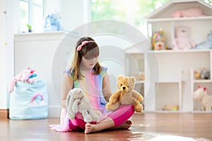 Little girl playing with doll house. Kid with toys