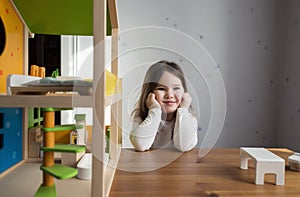 A little girl playing with dollhouse