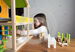 A little girl playing with dollhouse