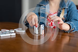 Little girl playing with dominoes at home on the table