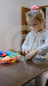 A little girl playing with Easter eggs from play dough decoration with beads. Cute children& x27;s crafts for Easter