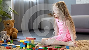 Little girl playing with educational toy blocks, early development school