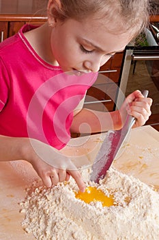 Little girl playing with egg in flour