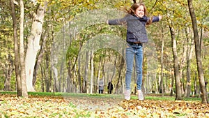 Little girl playing with fall leaves in city park. Kid having fun outdoors. Cute little blond child enjoying autumn