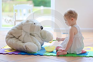 Little girl playing feeding her teddy bear