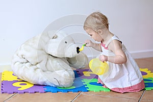 Little girl playing feeding her teddy bear