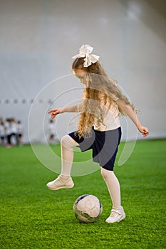 A little girl playing football holding your foot over the ball
