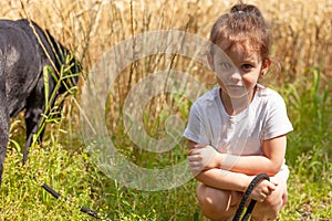 Little girl playing with a goat in a wheat field on a summer day