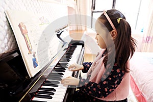 Little girl playing the piano at home