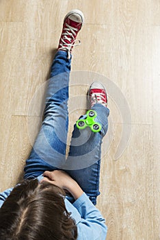 Little girl playing with green fidget spinner toy
