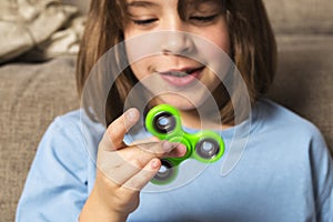 Little girl playing with green fidget spinner toy