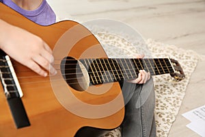 Little girl playing guitar on floor