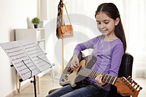Little girl playing guitar at music lesson