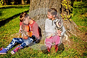 Little girl playing guitar in the park with husky puppy singing