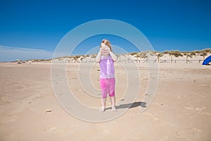 Little girl playing with hands in eyes at beach