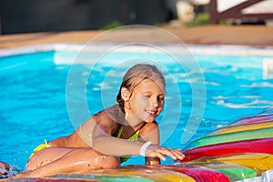 Little girl playing and having fun in swimming pool with air mat