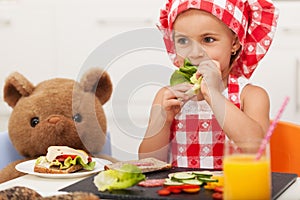 Little girl playing and having a healthy snack with her teddy be