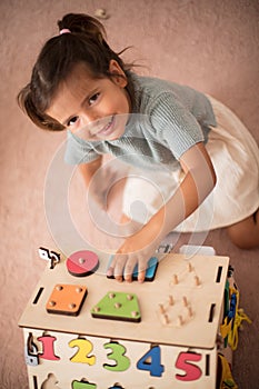 Little girl playing in her bedroom with wooden toy