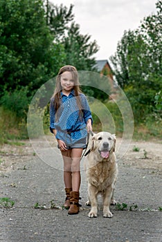 Little girl playing with her big dog outdoors in rural areas in summer