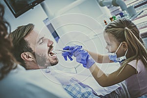 Little girl playing with her father at dentist office.