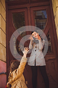 Little girl playing with her mom near old wooden door