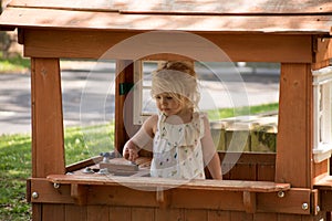 Little girl playing in her playhouse outside