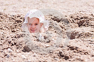 Little girl playing hide and seek hidden in a hole