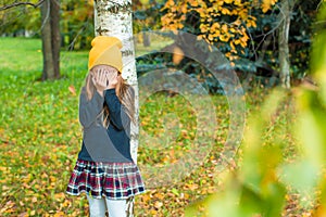 Little girl playing hide and seek near tree in