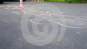 Little girl playing hopscotch in driveway