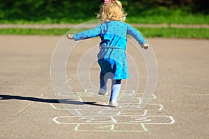 Little girl playing hopscotch on playground photo