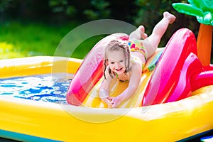 Little girl playing in inflatable garden swimming pool