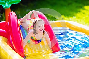Little girl playing in inflatable garden swimming pool