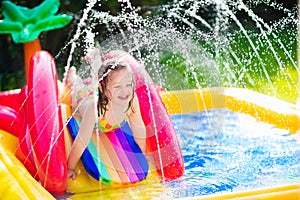 Little girl playing in inflatable garden swimming pool