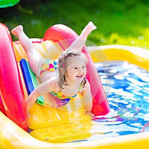 Little girl playing in inflatable garden swimming pool