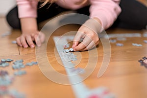 Little girl playing with a jigsaw confined at home by coronavirus