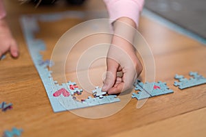Little girl playing with a jigsaw confined at home by coronavirus