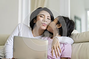 Little girl playing a laptop with her mother