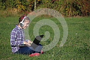 Little girl playing laptop and listening music on headphon