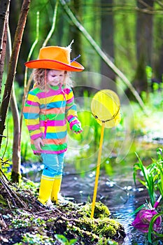 Little girl playing outdoors catching a frog