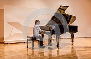 Little girl playing the piano at the concert