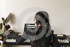 Little girl playing the piano at home. The child learns to play the keyboard