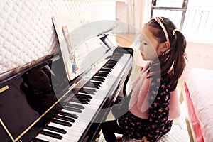 Little girl playing the piano at home