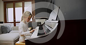 Little girl playing piano at home. Kid play piano in living room. Child learning piano at home. Music lesson, medium