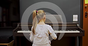 Little girl playing piano at home. Kid play piano in living room. Child learning piano at home. Music lesson, medium